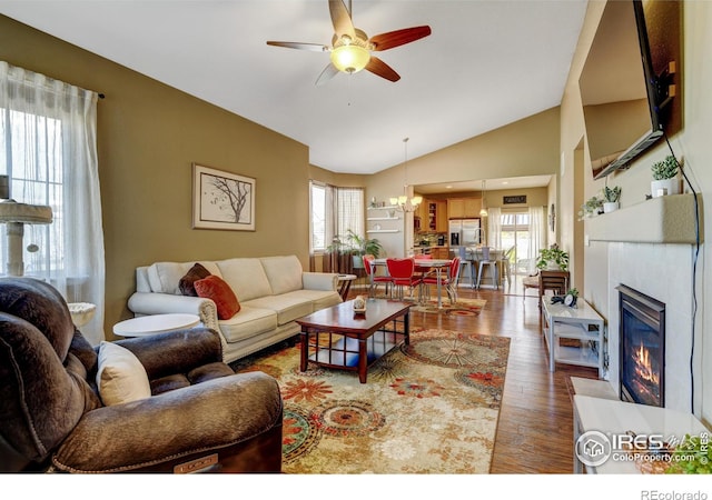 living room with plenty of natural light, wood-type flooring, lofted ceiling, and ceiling fan with notable chandelier