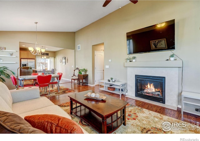 living room with a fireplace, wood-type flooring, ceiling fan with notable chandelier, and lofted ceiling