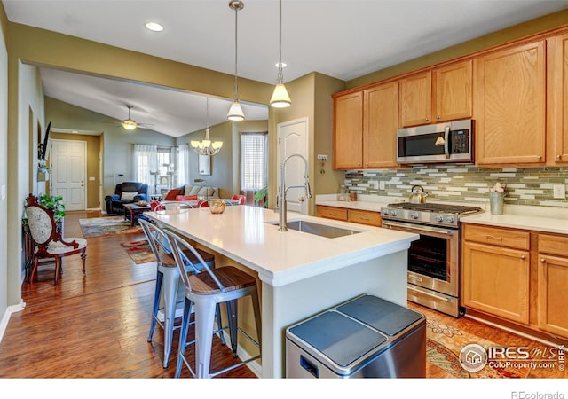 kitchen featuring sink, tasteful backsplash, lofted ceiling, a center island with sink, and appliances with stainless steel finishes