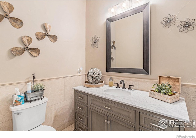 bathroom with vanity, toilet, and tile walls