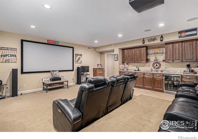 home theater room featuring bar area, light colored carpet, and wine cooler