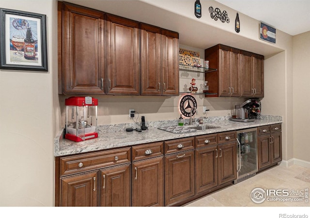 kitchen featuring light tile patterned floors, light stone countertops, sink, and beverage cooler