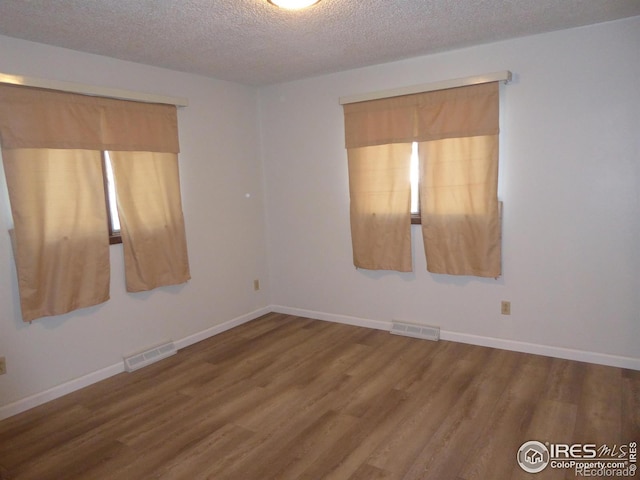 unfurnished room featuring wood-type flooring and a textured ceiling