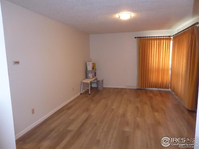 unfurnished room with hardwood / wood-style floors and a textured ceiling