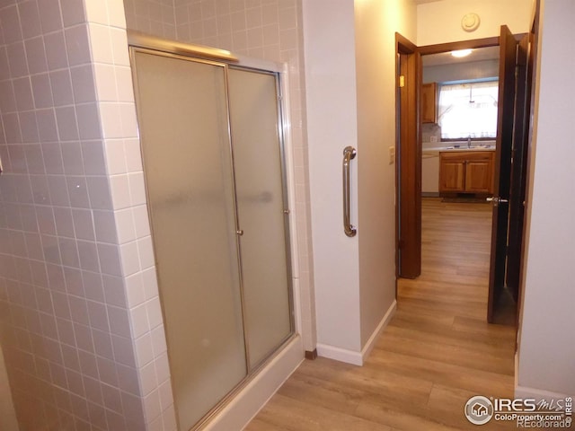 bathroom with hardwood / wood-style floors, a shower with shower door, and sink