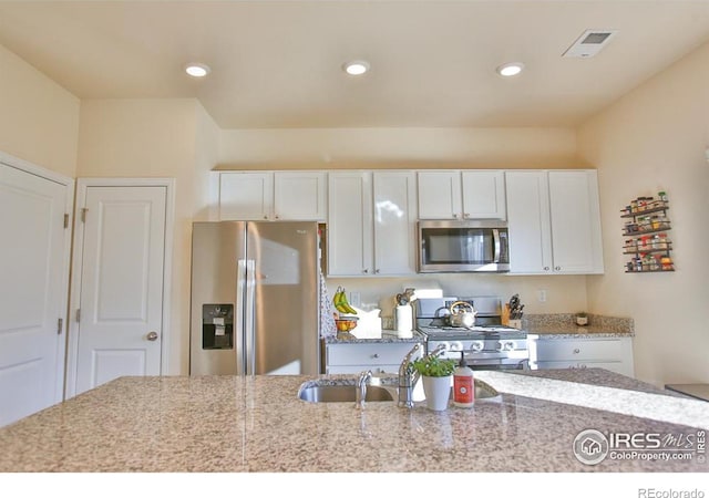 kitchen with white cabinetry, sink, stainless steel appliances, and light stone counters