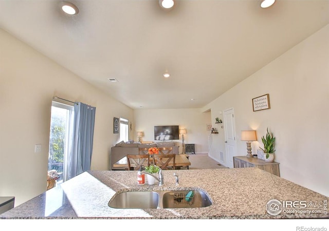 kitchen featuring carpet floors, an island with sink, light stone counters, and sink