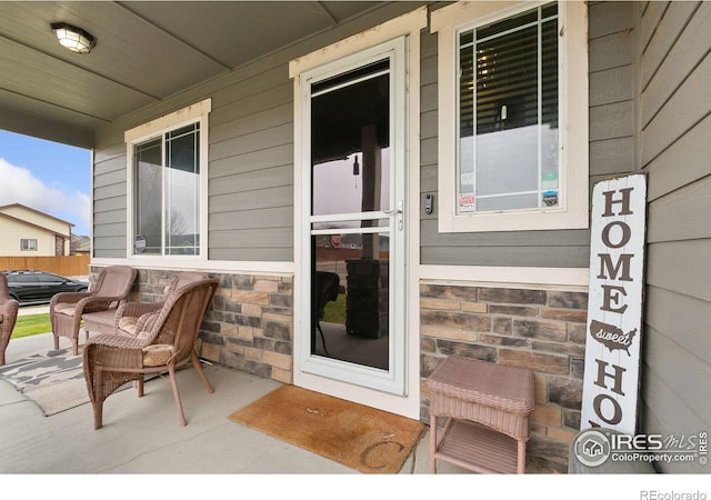 entrance to property featuring stone siding and a porch