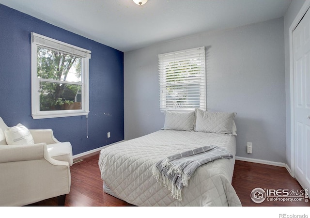 bedroom with multiple windows and dark wood-type flooring