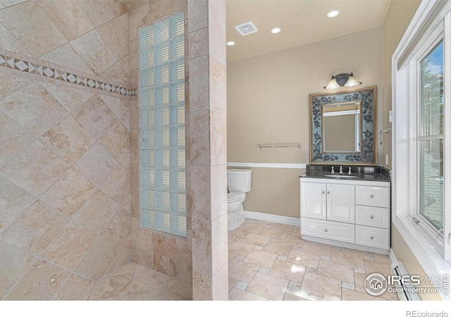 bathroom featuring vanity, toilet, and a tile shower