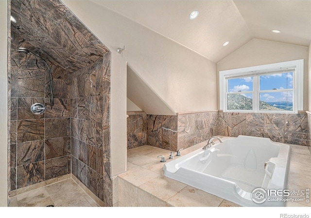 bathroom with vaulted ceiling and tiled bath