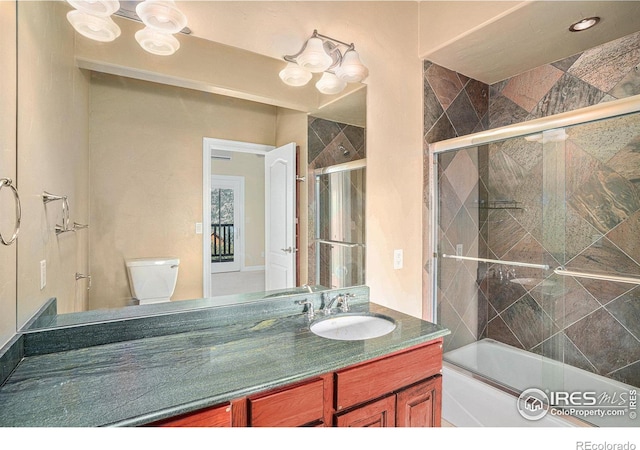 full bathroom featuring toilet, vanity, and shower / bath combination with glass door