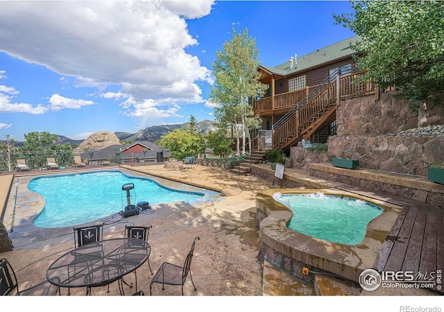 view of pool with a patio area, a hot tub, and a deck with mountain view