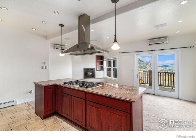 kitchen featuring island range hood, decorative light fixtures, stainless steel gas stovetop, light stone countertops, and a wall unit AC