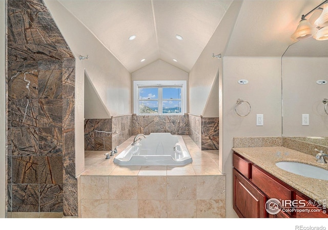 bathroom with vanity, vaulted ceiling, and tiled tub