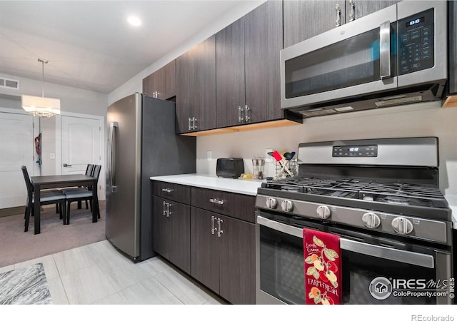 kitchen featuring decorative light fixtures, light tile patterned floors, dark brown cabinets, and appliances with stainless steel finishes