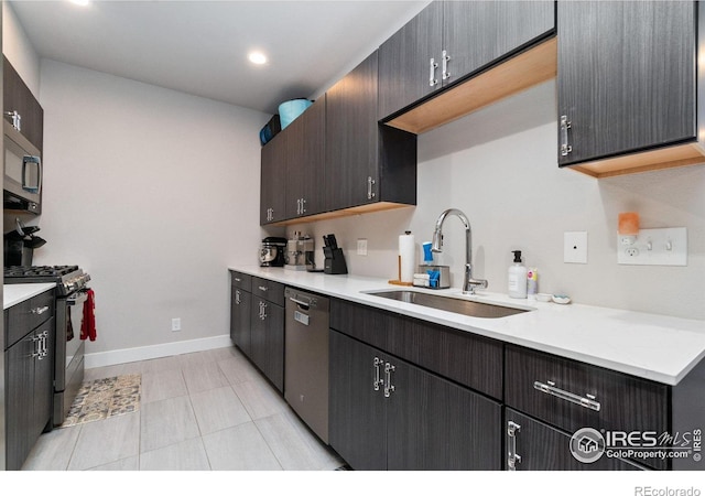 kitchen featuring appliances with stainless steel finishes, light tile patterned floors, dark brown cabinets, and sink