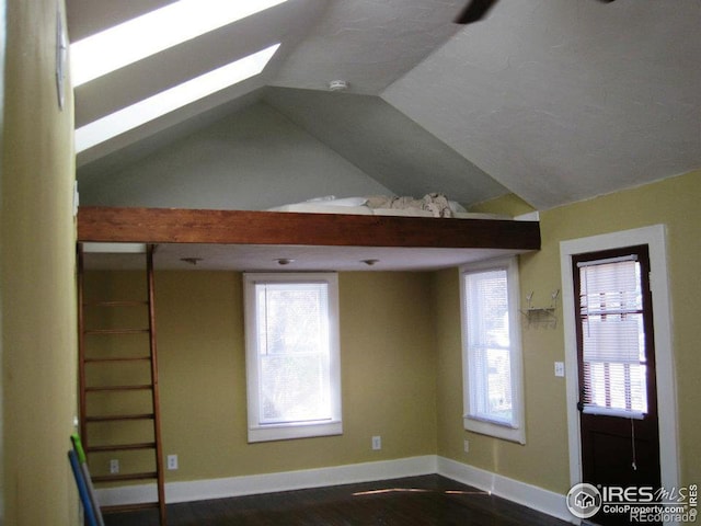 interior space featuring plenty of natural light, dark wood-type flooring, and vaulted ceiling