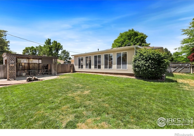 rear view of house with fence, a patio, and a yard