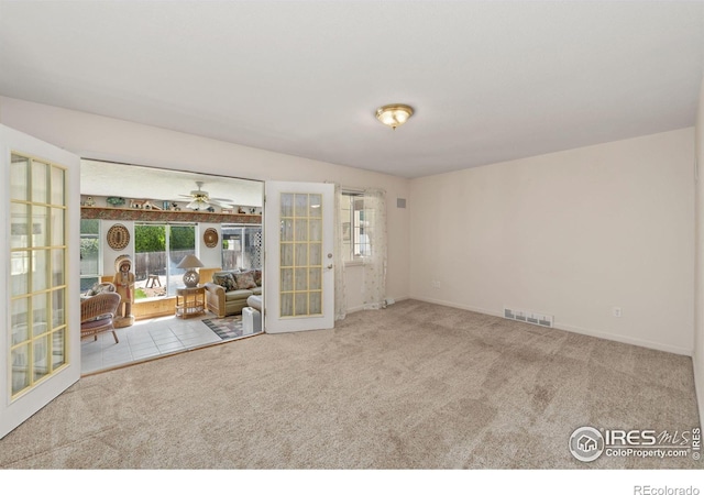 carpeted empty room featuring baseboards, visible vents, ceiling fan, and french doors