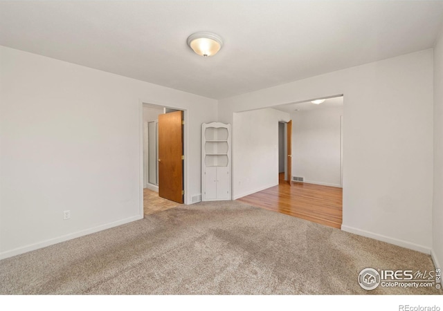 unfurnished room with carpet flooring, visible vents, and baseboards