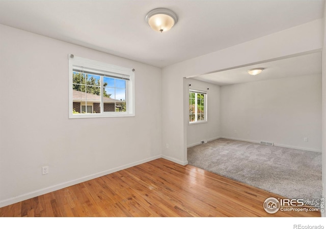 empty room featuring baseboards, visible vents, and wood finished floors