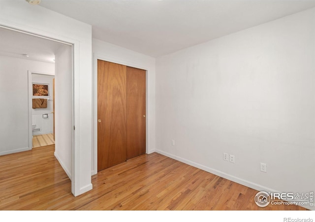 unfurnished bedroom with a closet, light wood-style flooring, and baseboards