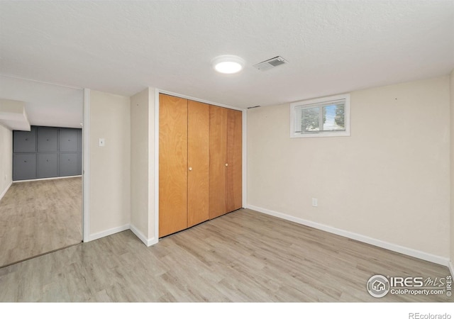 unfurnished bedroom with a textured ceiling, wood finished floors, visible vents, baseboards, and a closet