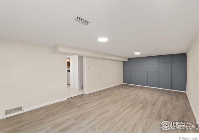 finished basement with light wood-type flooring, visible vents, and baseboards