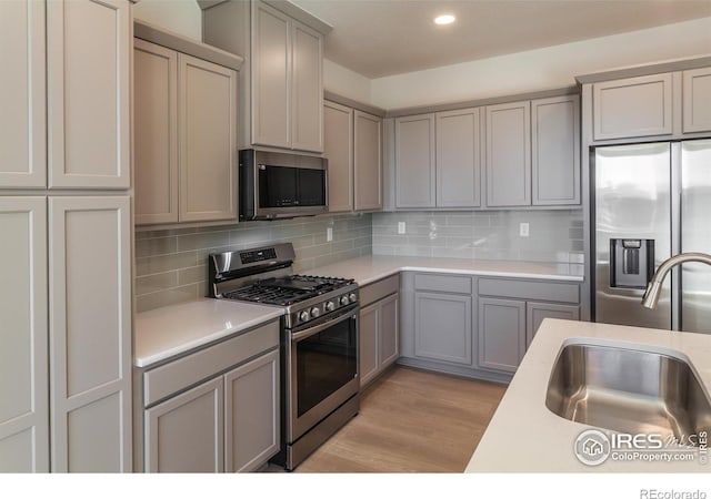5086 Mckinnon Ct, Timnath, CO 80547 - kitchen with appliances with stainless steel finishes, gray cabinetry, light countertops, decorative backsplash, and recessed lighting