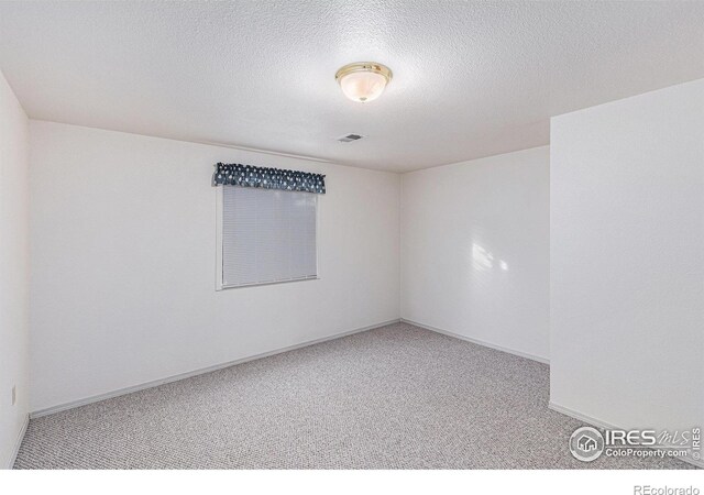 carpeted spare room featuring a textured ceiling