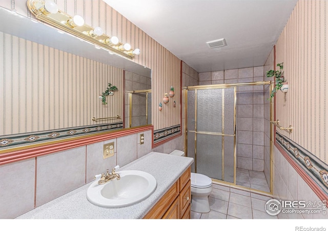 bathroom with tile patterned flooring, vanity, toilet, and walk in shower