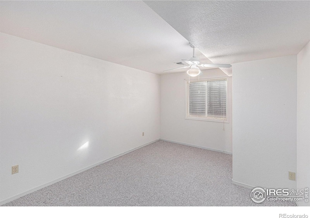 empty room with ceiling fan, light colored carpet, and a textured ceiling