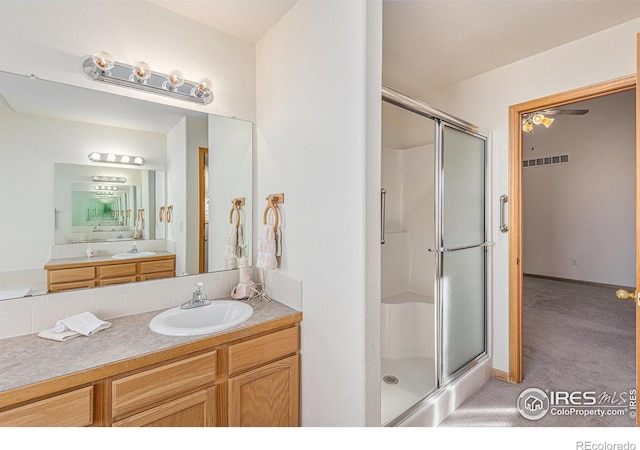 bathroom with ceiling fan, vanity, and walk in shower