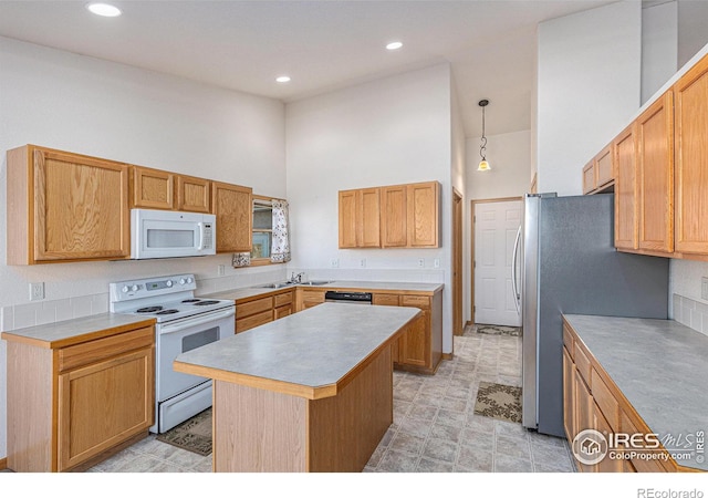 kitchen with white appliances, sink, pendant lighting, a high ceiling, and a kitchen island