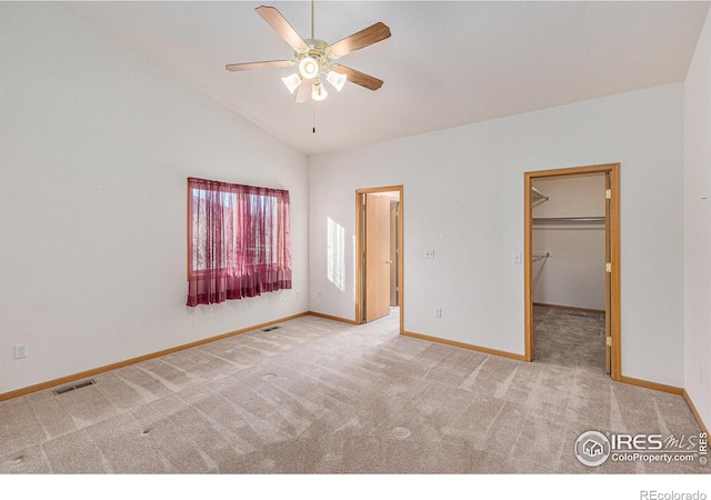 unfurnished bedroom with carpet, a walk in closet, ceiling fan, a closet, and lofted ceiling