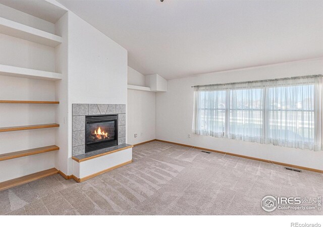 unfurnished living room with carpet, built in features, a fireplace, and vaulted ceiling