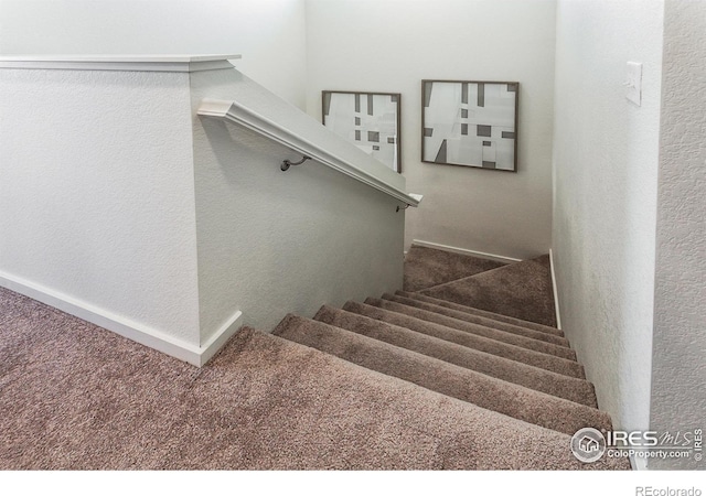 stairs featuring a textured wall and carpet
