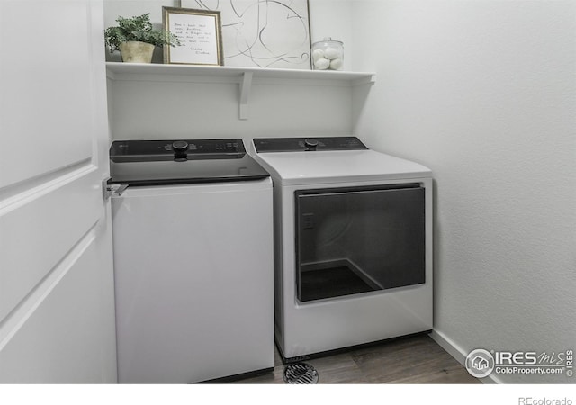 clothes washing area featuring washer and dryer, laundry area, baseboards, and wood finished floors