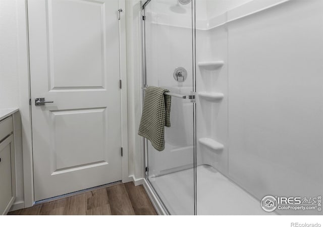 bathroom featuring a shower stall, vanity, and wood finished floors