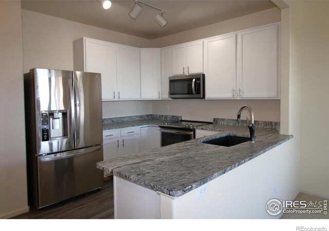 kitchen featuring white cabinetry, sink, light stone counters, kitchen peninsula, and appliances with stainless steel finishes