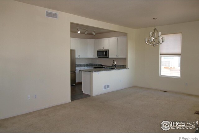 kitchen with kitchen peninsula, carpet flooring, stainless steel appliances, white cabinetry, and hanging light fixtures