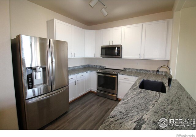 kitchen with sink, dark hardwood / wood-style floors, light stone countertops, white cabinetry, and stainless steel appliances