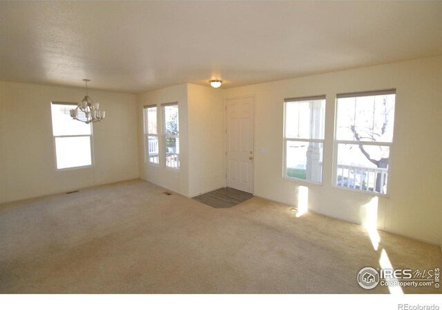 interior space with carpet flooring, plenty of natural light, and an inviting chandelier