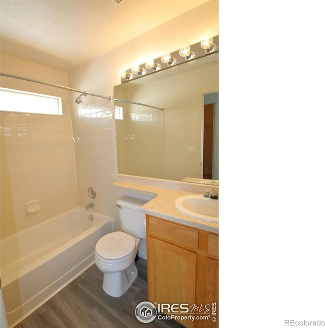 full bathroom with hardwood / wood-style floors, vanity, toilet, and tiled shower / bath