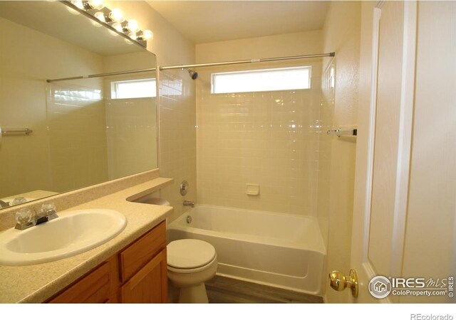 full bathroom with hardwood / wood-style flooring, vanity, toilet, and tiled shower / bath