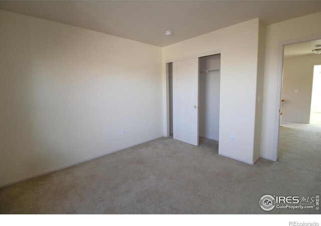 unfurnished bedroom with light carpet and a closet