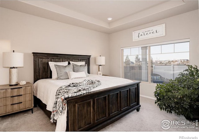 bedroom with a tray ceiling and light colored carpet