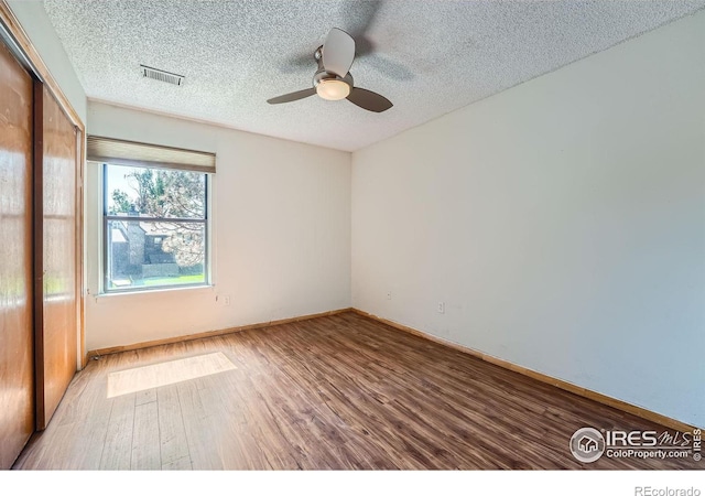 empty room featuring ceiling fan, hardwood / wood-style floors, and a textured ceiling