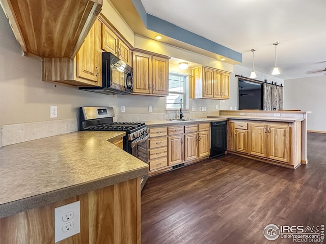 kitchen with sink, hanging light fixtures, kitchen peninsula, a barn door, and black appliances